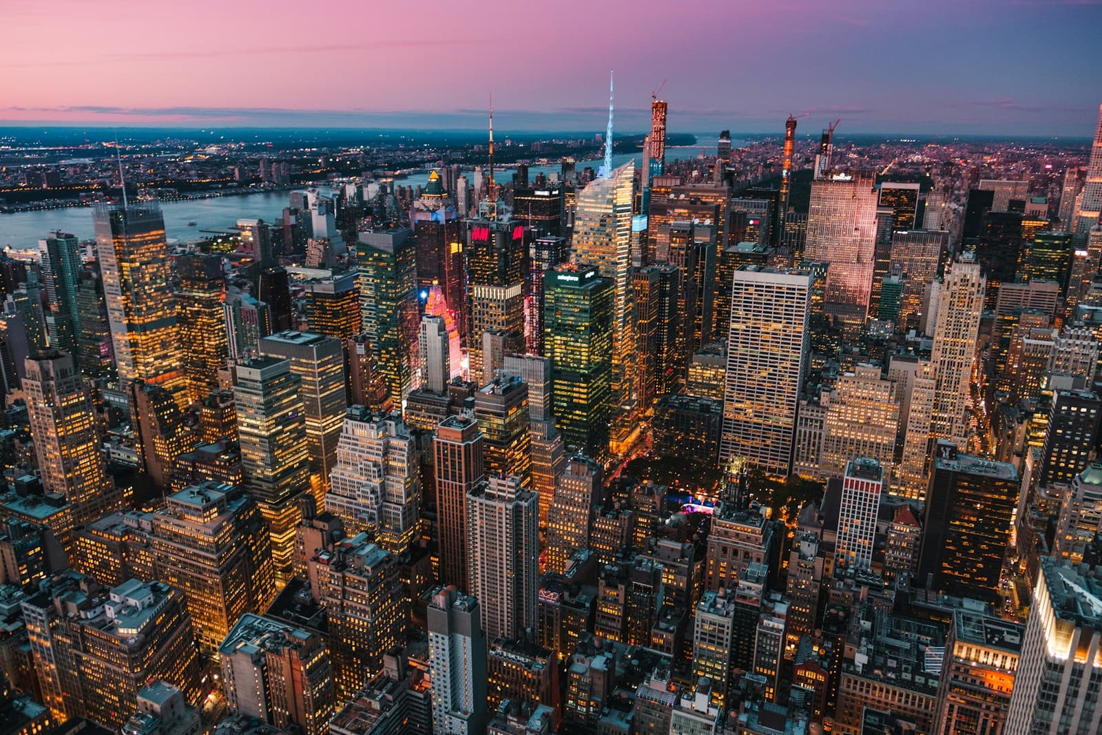 An aerial view of Manhattan and its illuminated skyscrapers at dusk