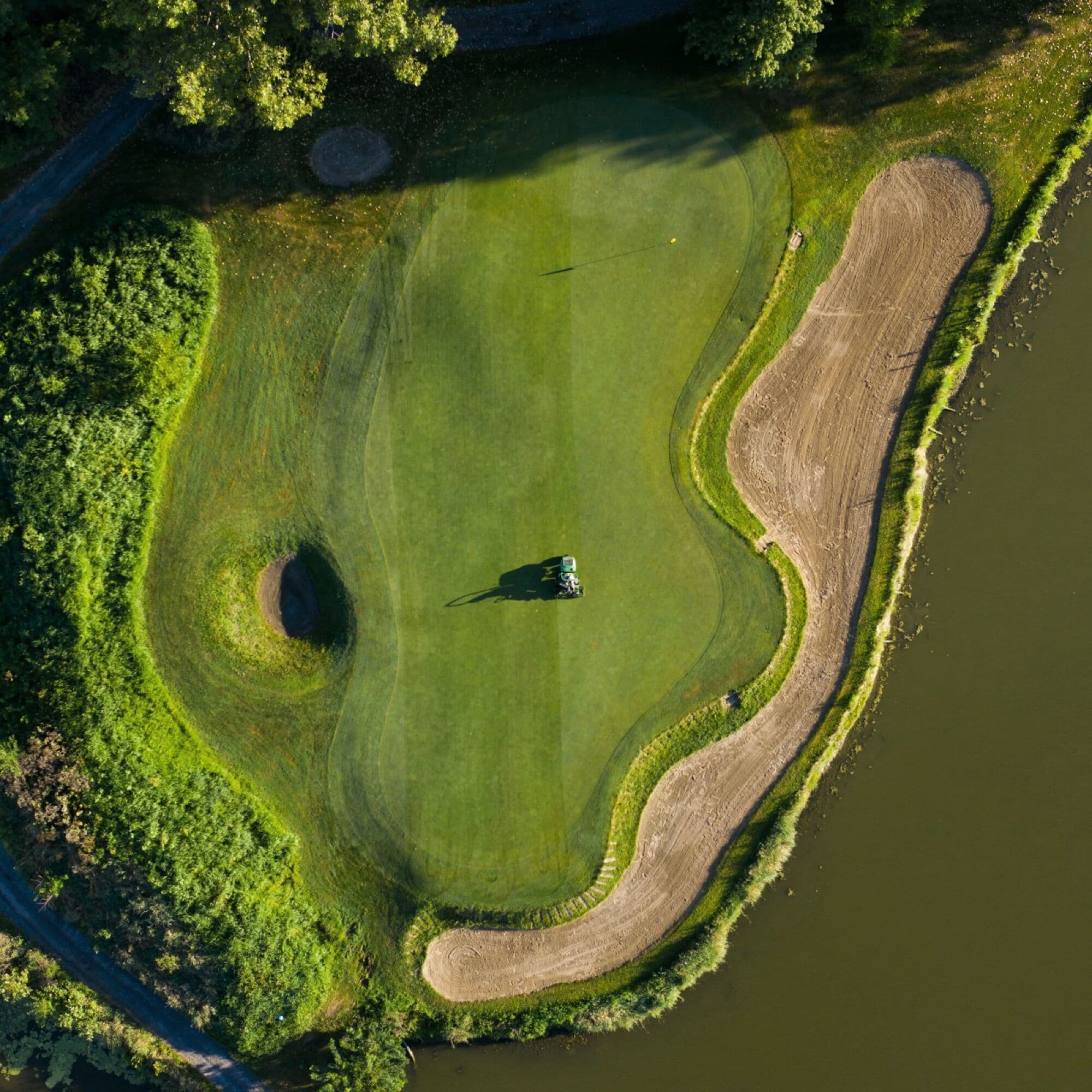 An aerial view of a golf green beside a sand bunker